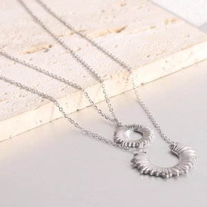 Macro detail of silver double-layer necklace with sunburst and half-sun pendants