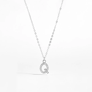 Macro shot of silver letter Q pendant with sparkling cubic zirconia on a delicate chain
