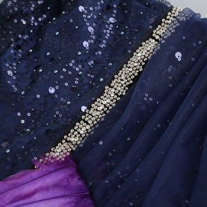 Détail du tissu à paillettes bleu marine avec bordure perlée et ourlet en plumes violettes