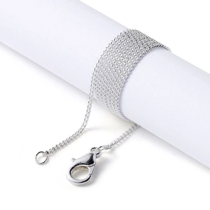 Detail view of silver chain wrapped on white stand with lobster clasp for DIY jewelry