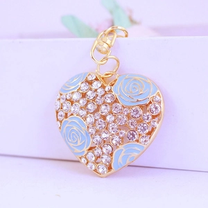 Porte-clés cœur doré avec rose en émail bleu et strass brillants sur fond lilas
