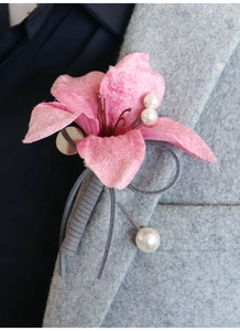 Detail of pink velvet flower boutonniere with pearl accents on a grey tweed blazer lapel