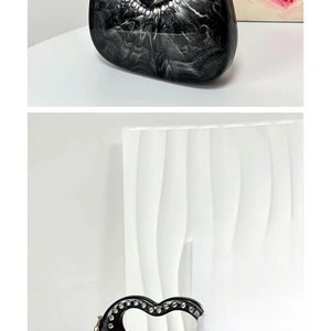 Detail of evening bag with black marble texture and rhinestone heart handle