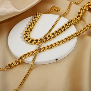Detail of gold-plated Cuban link anklets with polished finish on a silk background
