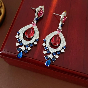 Macro shot of vintage silver earrings featuring red and blue teardrop stones with zircon