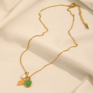 Detail of 18K gold plated necklace with pearl, shell pendant and green gemstone charm