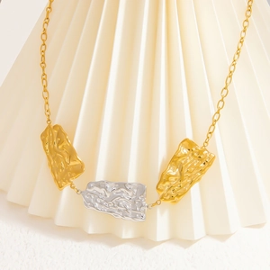 Macro detail of mixed gold and silver pendants with irregular crinkle texture
