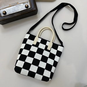 Detailed close-up of a black and white checkerboard knit tote with leather handles