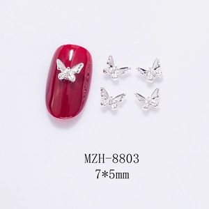 Macro shot of a 7x5mm silver metal butterfly nail charm with tiny rhinestones on red tip