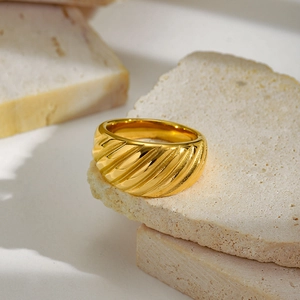 Macro shot of minimalist gold textured ring with diagonal lines on beige natural stones