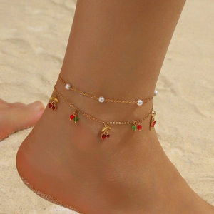 Double-layer gold stainless steel anklet with pearls and red cherry charms on beach
