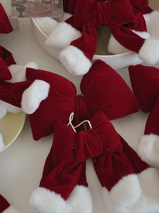 Close-up of red velvet Christmas bows with white faux fur trim on a minimalist background