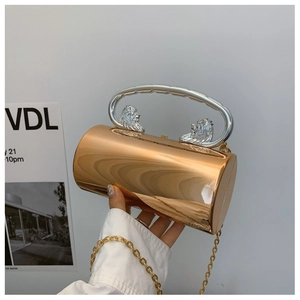 Detailed macro of golden cylindrical evening bag with silver lion head handles