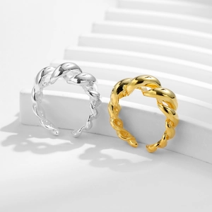 Polished silver and gold twisted rope open rings on minimalist geometric display