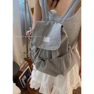 Detail of light blue fabric backpack with drawstring closure and soft pink plush charm