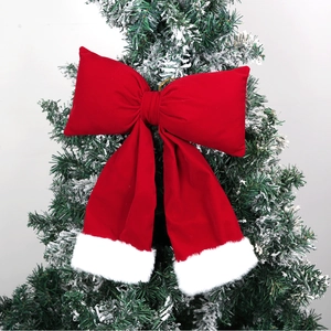 Detail of red velvet Christmas bow with white plush trim on snow-dusted tree top