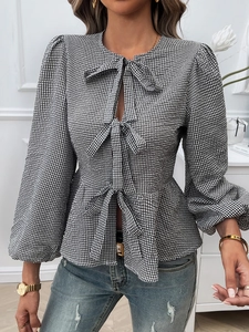 Detailed view of women's long puff sleeve top featuring black and white plaid and three front bows