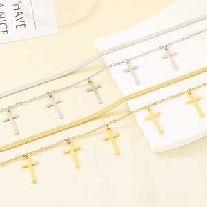 Detail of layered gold and silver cross necklaces on a minimalist marble background