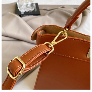 Close-up of golden metal hardware and premium brown leather texture on a woven handbag