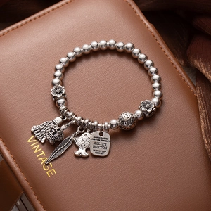 Close-up of vintage beaded bracelet with charms like feathers and lucky cat on leather