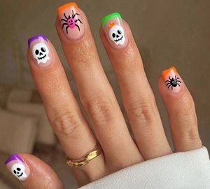 Close-up of Halloween press-on nails with skull and spider art in macaron colors