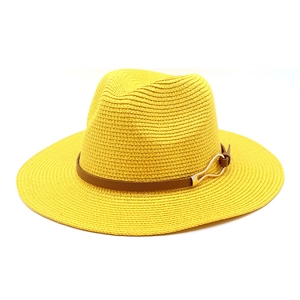 Close-up of bright yellow woven straw fedora with brown leather band and gold metal buckle