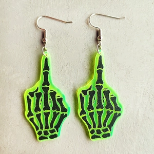 Detail of neon green acrylic skeleton hand earrings featuring black bone patterns and silver hooks