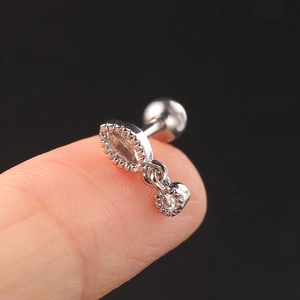 Macro view of silver geometric zircon cartilage earring held on a fingertip for size