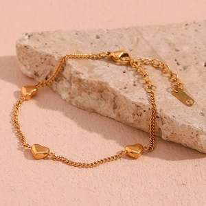 Detail of 18K gold plated stainless steel bracelet with three heart charms on a stone