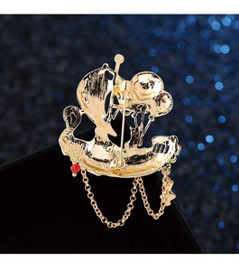 Detailed close-up of a golden sailboat brooch with hanging metal chains and red accents