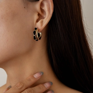 Détail de boucles d'oreilles dorées en C avec tissu noir sur le mannequin