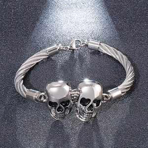 Détail du bracelet câble en acier inoxydable argenté avec deux têtes de mort punk