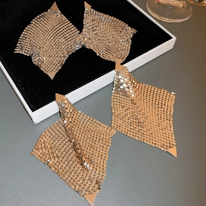 Détail de boucles d'oreilles triangulaires irrégulières en maille dorée pailletée