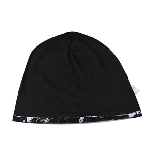 Gros plan du bonnet en tricot noir avec ourlet floral et étiquette de lavage latérale