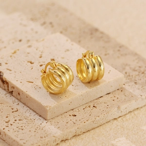 Detailed view of gold multi-layer hoop earrings displayed on natural stone pedestals