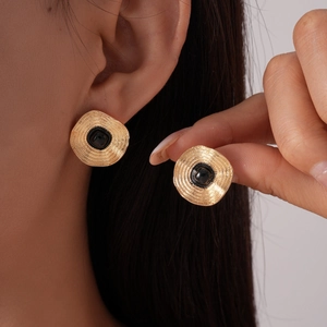 Boucles d'oreilles vintage carrées dorées avec pierre noire et textures sur le mannequin