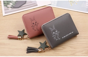 Detail of pink and grey zipper coin purses with tassel charms and rabbit patterns