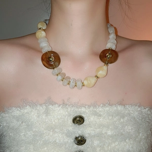 Detail of acrylic irregular beads necklace with gold spacers worn by a model