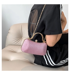 Pink glitter clutch bag with gold handle and chain strap shown in a lifestyle scene