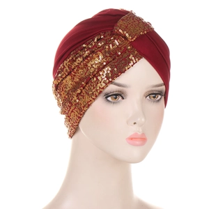 Detailed view of burgundy turban hat with shimmering gold sequins on a mannequin head