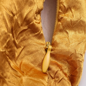 Detailopname van gouden satijnen textuur en onzichtbare rits op de jurk