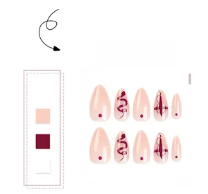Detail of almond press-on nails with snake patterns and cross art in burgundy and nude