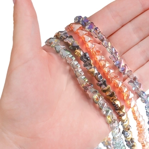 Hand holding vibrant gradient butterfly-shaped glass crystal beaded bracelets for DIY jewelry