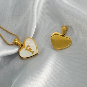 Gold heart initial necklace with natural mother of pearl on a silk fabric background