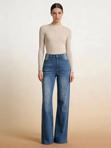 Dettaglio di jeans blu a vita alta e gamba larga con lavaggio baffato e maglione a costine