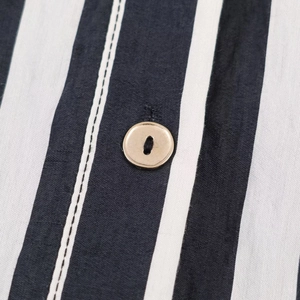 Detail shot of vertical black and white striped fabric with a beige button fastening