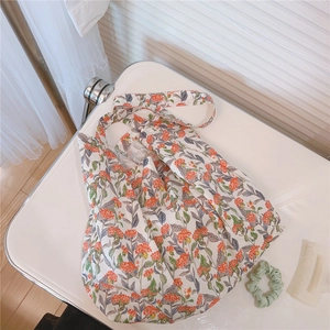 Détail d'un sac cabas en coton à motifs floraux orange et feuilles vertes sur table