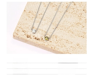 Detail of titanium steel heart necklaces with green and clear zircon pendants on stone