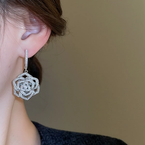 Macro view of silver floral dangle earrings featuring zircon stones on a model