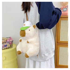 Detail of cute beige plush Capybara backpack with a C-letter baseball cap worn by model